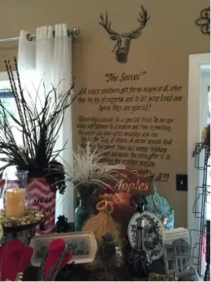 Wall imprint defining *surcee*, with a collection of small gifts on a table in the foreground