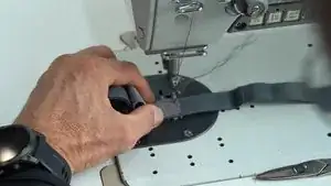 Ergänzendes Video zu Schritt 5. Es wird gezeigt, wie die erste Seite des Gummibands auf dem Brustgurt festgenäht wird.