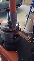 Crankshaft in a specialized tool designed to fix the crankshaft half while a press removes the pin from that half of the crankshaft.