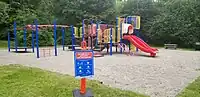 The same playground, re-opened, with signage cautioning that special care should still be taken due to COVID-19.